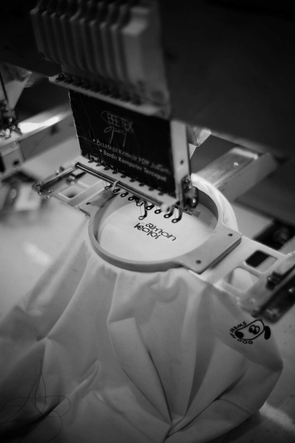 Embroidery machine stitching a logo onto white fabric